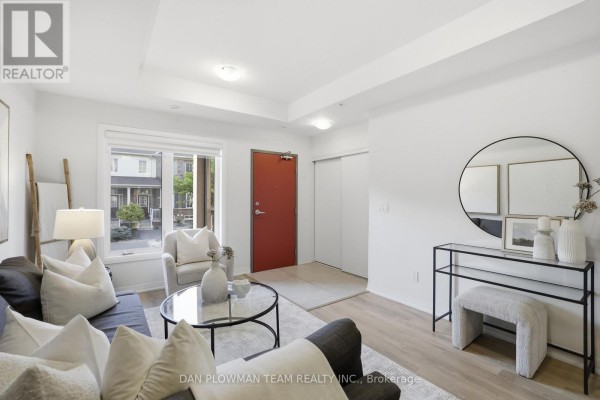 Living room with grey sofa, round coffee table, console table, and red door. - 1210 - 2635 William Jackson Drive, Pickering