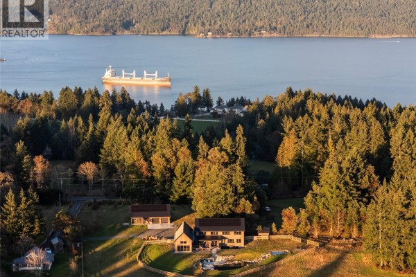 View of the home with a shipping vessel in the distance, surrounded by forest. - 1210 Cherry Point Rd, Cobble Hill