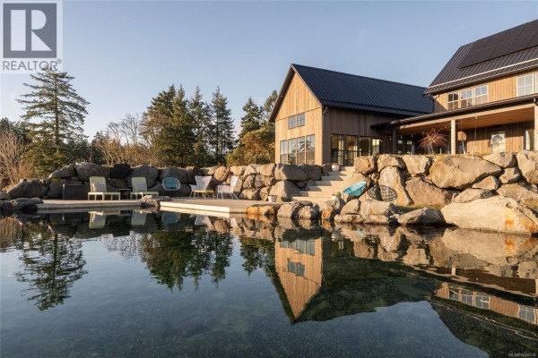 Close-up of the pond with large rocks and seating area beside the home. - 1210 Cherry Point Rd, Cobble Hill