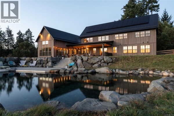 Evening view of the house with illuminated windows and pond reflection. - 1210 Cherry Point Rd, Cobble Hill