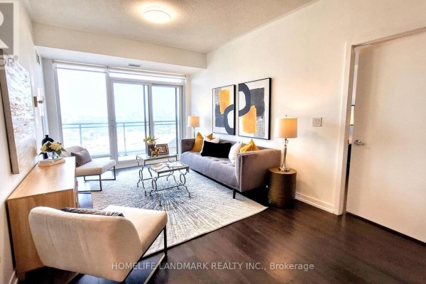 Living room with grey sofa, yellow accent pillows, glass coffee table, and dark hardwood floors. - 1211 - 2520 Eglinton Avenue W, Mississauga