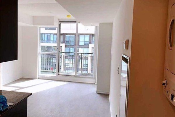 An empty living area with light grey floors and a sliding glass door to a balcony. - 1211 - 3091 Dufferin Street, Toronto