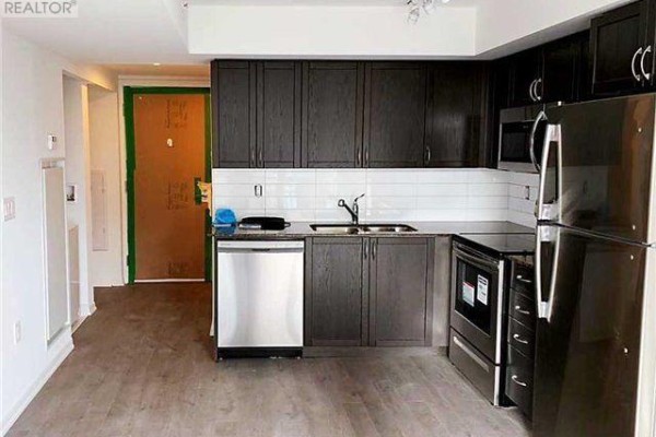 A spacious kitchen with dark wood cabinets, white subway tile backsplash, and stainless steel appliances. - 1211 - 3091 Dufferin Street, Toronto