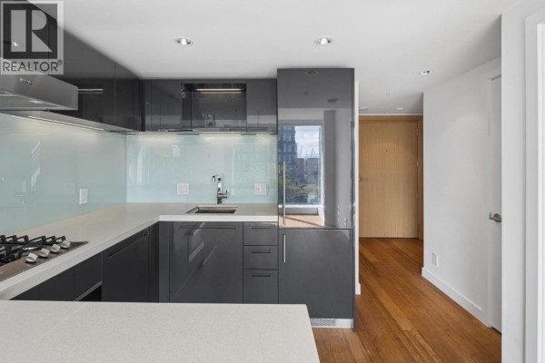 Modern kitchen with grey cabinets, white quartz countertops, and a light blue glass backsplash. - 1211 777 Richards Street, Vancouver
