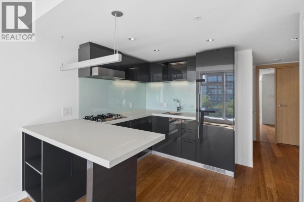 U-shaped kitchen with dark grey cabinets, white quartz island, and stainless steel appliances. - 1211 777 Richards Street, Vancouver