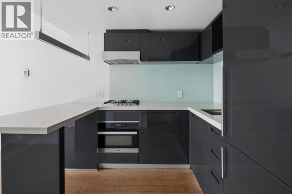 Kitchen with dark grey high-gloss cabinets, white countertops, gas stove, and built-in oven. - 1211 777 Richards Street, Vancouver