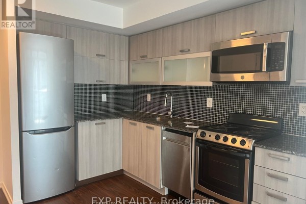 Kitchenette with a stainless steel refrigerator, stove, microwave, and grey cabinetry. - 1212 - 36 Lisgar Street, Toronto