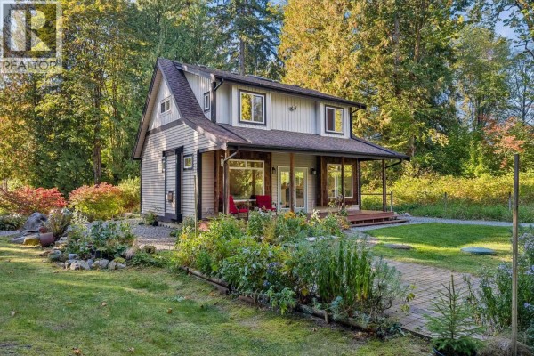 A two-story house nestled among trees with a gravel path and garden. - 12121 264 Street, Maple Ridge