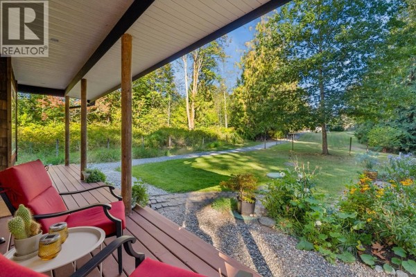 View from the covered porch of a house overlooking a green lawn and trees. - 12121 264 Street, Maple Ridge