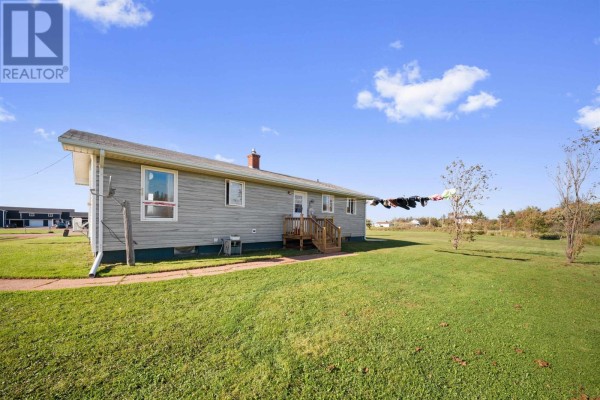 Rear exterior of the light grey house with a wooden deck and clothesline in the yard. - 12122 Rte 14, Pleasant View