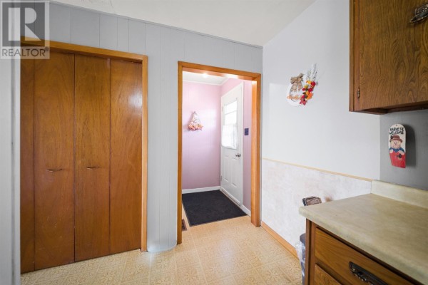 Interior view of a hallway with wood doors, a coat closet, and a pink wall leading to the front door. - 12122 Rte 14, Pleasant View