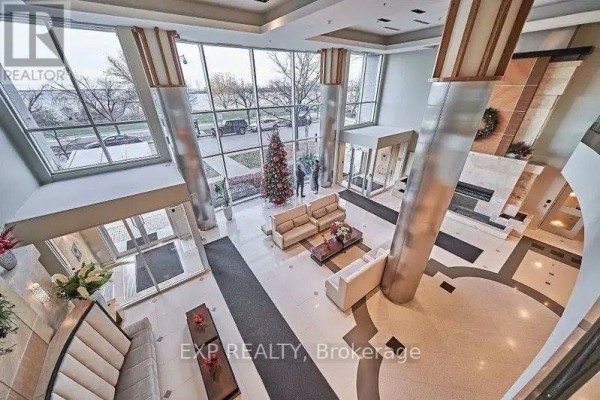Spacious condo lobby with cream sofas, marble floors, and large windows. - 1213 - 58 Marine Parade Drive, Toronto