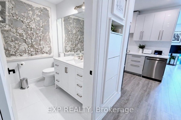 A bright white bathroom with a double vanity, large mirror, and a wall art depicting flowers. - 1213 - 58 Marine Parade Drive, Toronto