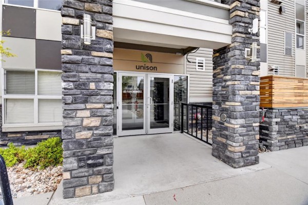 Close-up of the building entrance with stone pillars and glass double doors. - 1213 65 Fiorentino Street, Winnipeg