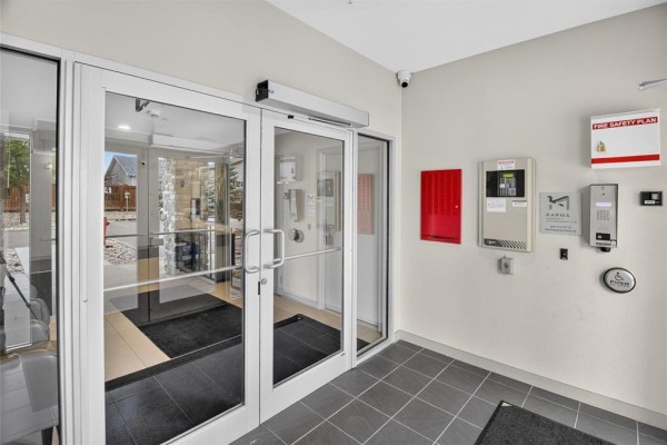Interior view of the building's entrance lobby with glass doors and security system panels. - 1213 65 Fiorentino Street, Winnipeg