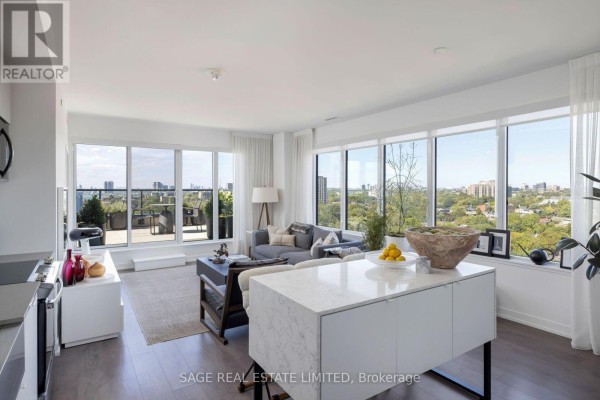 Open concept living space with large windows, grey sofa, coffee table, and access to a balcony. - 1214 - 270 Dufferin Street, Toronto