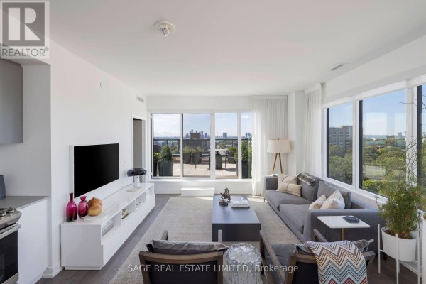 Living room features a grey sectional sofa, dark coffee table, and entertainment unit with a television. - 1214 - 270 Dufferin Street, Toronto