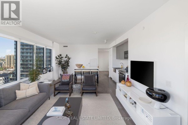 View of dining area and kitchen from the living room, with large windows and city views. - 1214 - 270 Dufferin Street, Toronto