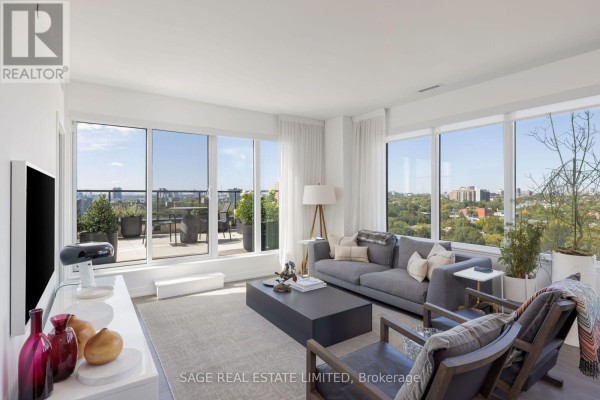 Spacious living room with a grey sofa, armchair, coffee table, and floor-to-ceiling windows. - 1214 - 270 Dufferin Street, Toronto