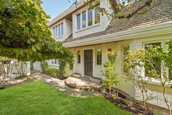 Front entrance of a white brick house with a dark brown door and a curved walkway. - 12141 Sullivan Street, Surrey