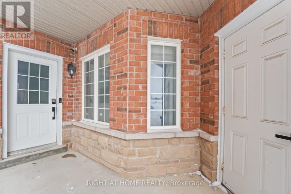 Covered porch with red brick and light stone exterior walls, white doors, and windows. - 1216 Fox Hill Street, Innisfil