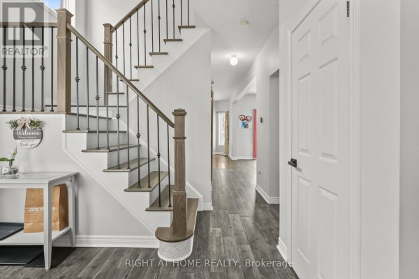 Interior view of a home's entryway with gray wood floors, white doors, and a staircase. - 1216 Fox Hill Street, Innisfil