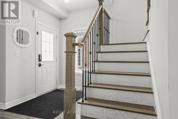 Close-up of a staircase with gray wood treads and risers, black spindles, and light wood railing. - 1216 Fox Hill Street, Innisfil