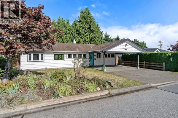 Front view of a white residential house with a paved driveway and carport. - 1216 Pinewood Crescent, North Vancouver
