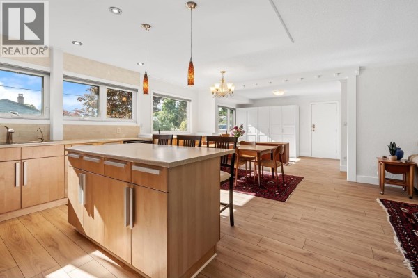Open concept kitchen and dining area with a large island and wooden floors. - 1216 Pinewood Crescent, North Vancouver