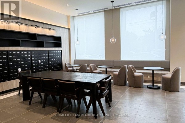 Communal area with mailboxes, a long dining table, and seating near large windows. - 1217 - 1 Jarvis Street, Hamilton