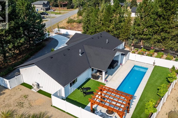 Aerial view of the white house backyard, featuring a pool, hot tub, and pergola. - 1217 Mcphee Road, Castlegar