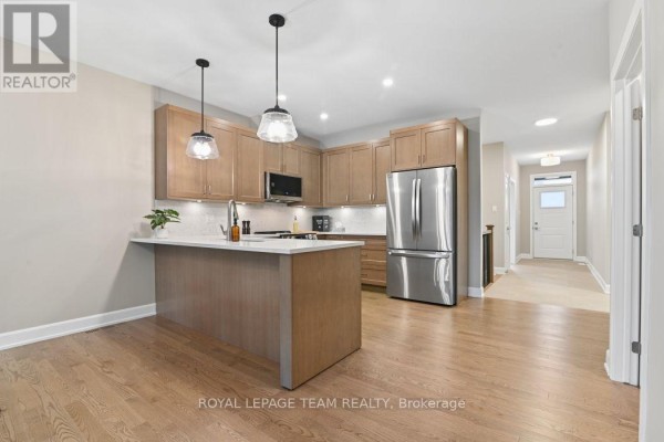 Kitchen island, stainless steel appliances, wood cabinets, and hardwood floors - 1217 Potter Drive Brockville