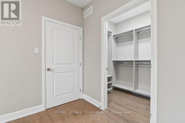Walk-in closet with shelving and hanging rods next to a closed door - 1217 Potter Drive Brockville