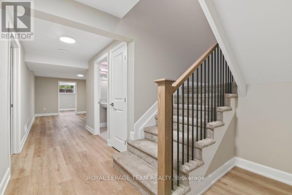 Renovated basement hallway with stairs and wood floors - 1217 Potter Drive Brockville
