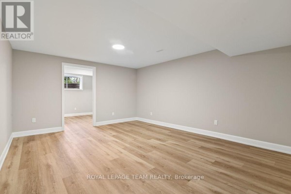 Renovated basement room with laminate flooring and a doorway - 1217 Potter Drive Brockville