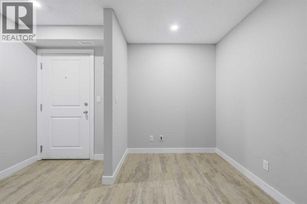 Open concept living and dining area with grey flooring, a fireplace, and furniture. - 1219, 625 Glenbow Drive, Cochrane
