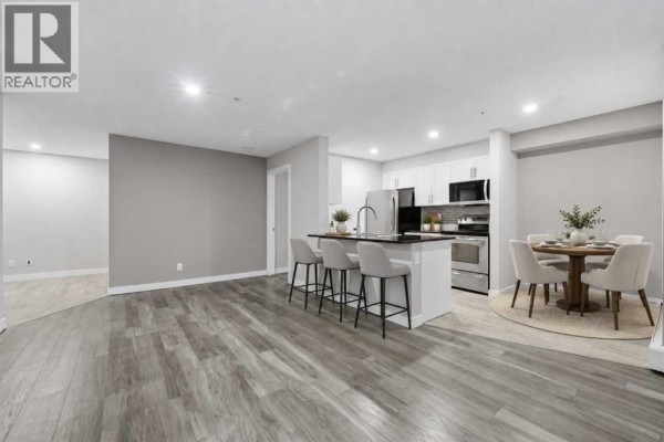 Living room with a large window, balcony access, sofa, recliner, and view of the outdoors. - 1219, 625 Glenbow Drive, Cochrane