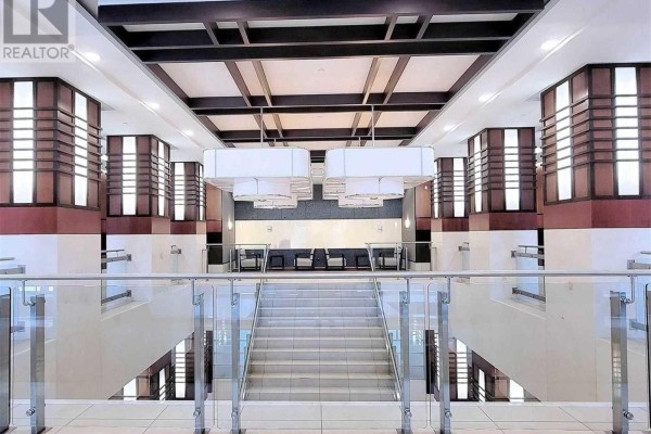 Modern lobby with a grand staircase, glass railings, and decorative lighting fixtures. - 1219 - 33 Cox Boulevard, Markham
