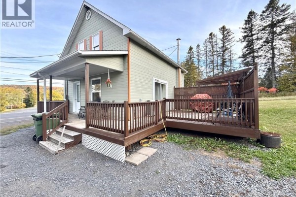 Side exterior view of the house showing the deck, porch, and surrounding trees. - 1219 St-francois Street, Verret