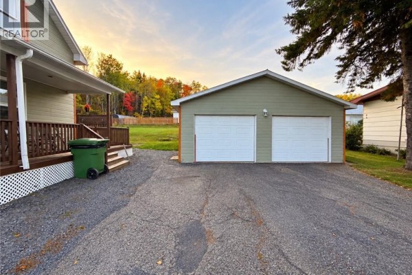 Driveway leading to a detached two-car garage with white doors. - 1219 St-francois Street, Verret
