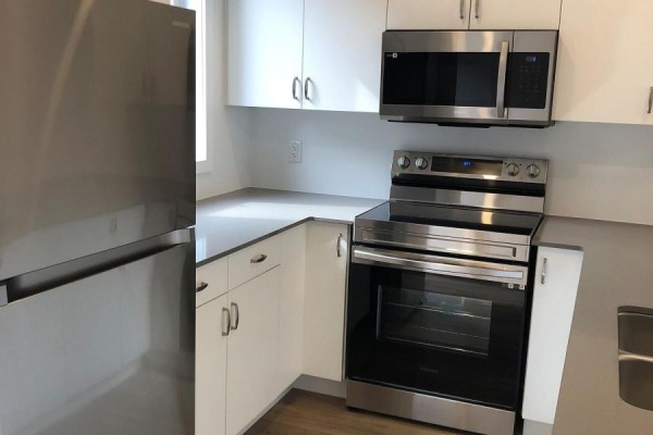 Corner kitchen view showing stainless steel oven, double sink, and grey countertops. - 122 - 781 Clare Avenue, Welland