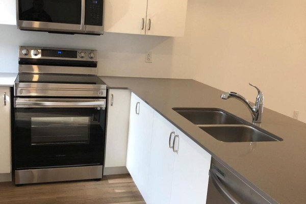 Close-up of kitchen island with double sink, chrome faucet, and grey countertop. - 122 - 781 Clare Avenue, Welland