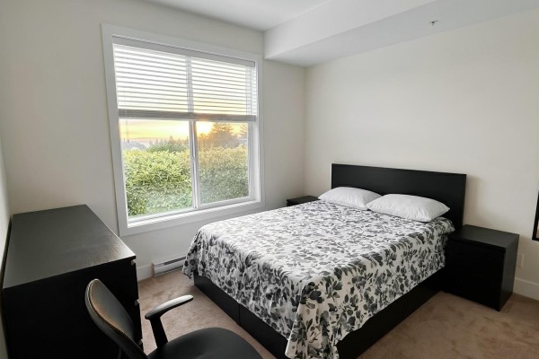Bedroom with a queen-sized bed, black nightstands, dresser, and a large window with a view. - 122 15956 86a Avenue, Surrey