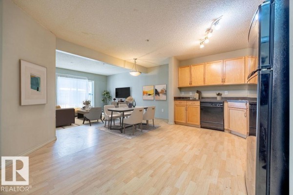 Bedroom with light gray walls, a queen bed, wall-mounted TV, and a window overlooking outside. - #122 646 Mcallister Lo Sw, Edmonton