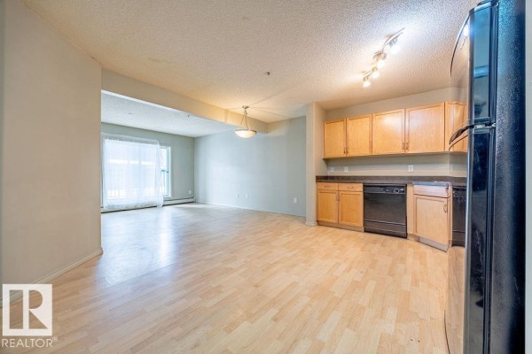 Bathroom with a white bathtub and shower, light wood vanity, dark countertop, and tiled floor. - #122 646 Mcallister Lo Sw, Edmonton