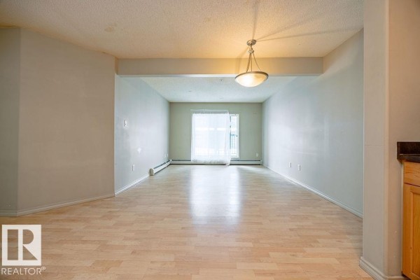 Open concept kitchen and living area with light wood cabinets, black appliances, and laminate flooring. - #122 646 Mcallister Lo Sw, Edmonton