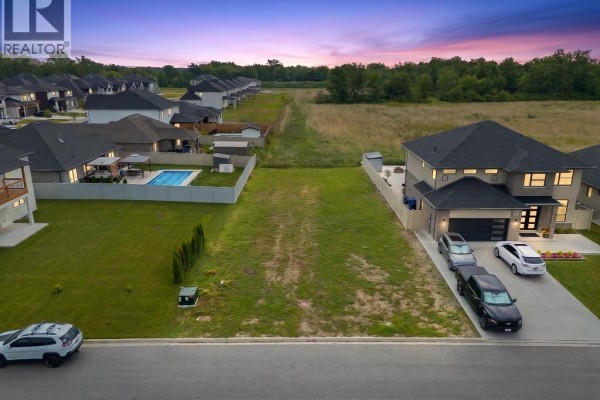 Aerial view of a suburban street with houses, yards, and a pool at sunset. - 122 Davis, Amherstburg