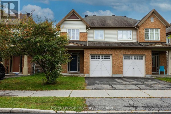 Front view of the townhouse exterior with a manicured lawn and sidewalk. - 122 Highbury Park Drive S, Ottawa