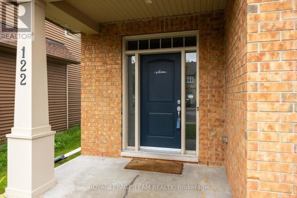 Close-up of the townhouse front entrance with a dark blue door and sidelight windows. - 122 Highbury Park Drive S, Ottawa