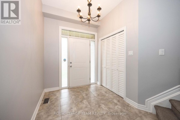 Interior foyer with tiled floor, white doors, a chandelier, and a closet. - 122 Highbury Park Drive S, Ottawa